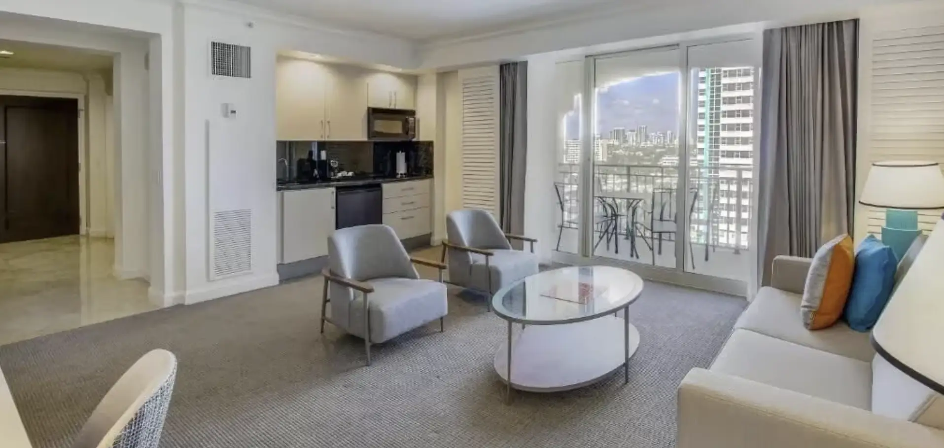 Spacious suite with living area, sofa, chairs, kitchenette and balcony access
